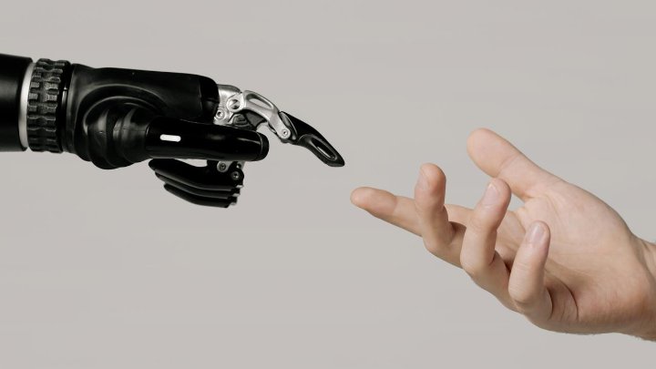 Picture of robotic hand reaching out to a human hand like the image of God and Adam reaching towards one another in the Sistine Chapel